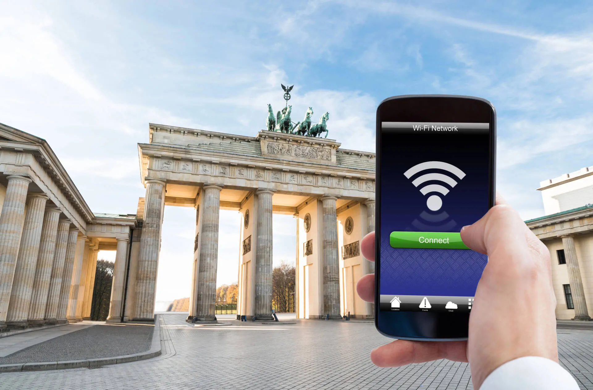 Hand holding smartphone displaying Wi-Fi network connection screen in front of Brandenburg Gate, Berlin