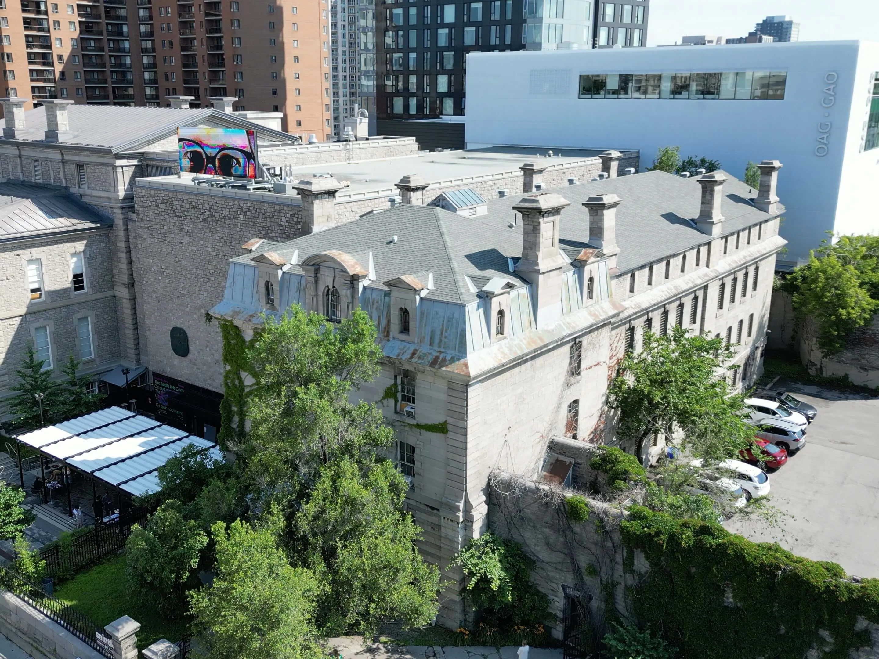 Historic stone mansion with mansard roof surrounded by modern downtown Ottawa apartment towers and office buildings.
